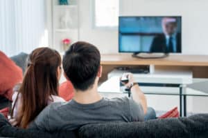 Rear view of Asian couple watching television in living room; Facebook is launching new TV app