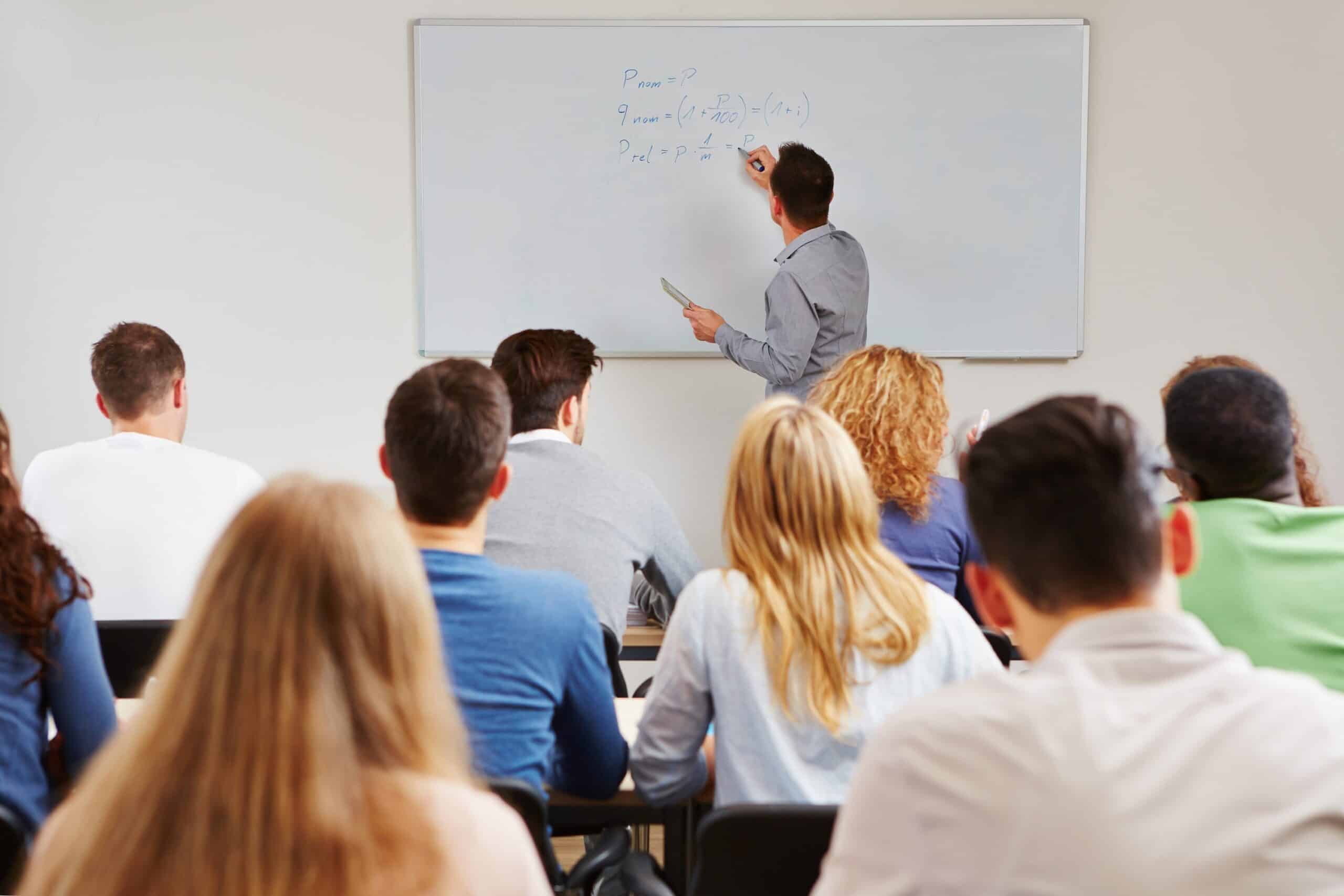 Instructor writing on whiteboard in front of students. What is Lecture Capture?