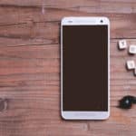 Smartphone and headphones on wooden background with lettered cubes spelling YouTube. 8 Tips for Better YouTube SEO