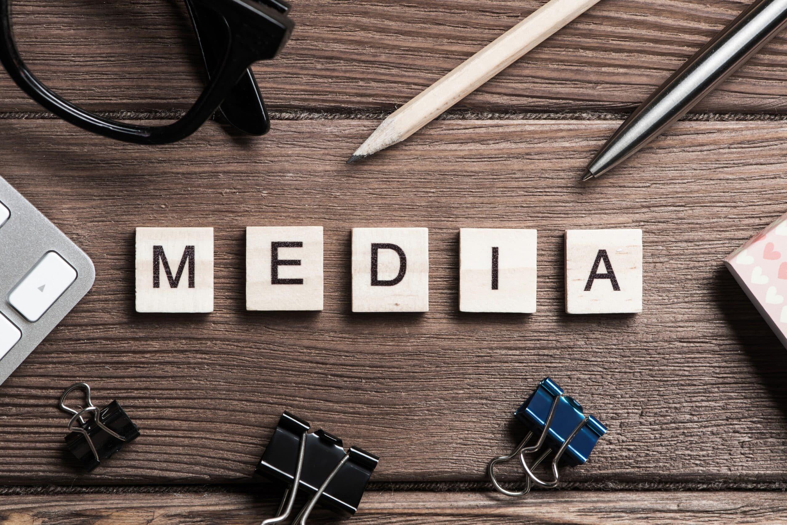 Workspace desk with word media spelled in wooden blocks. captioned online video