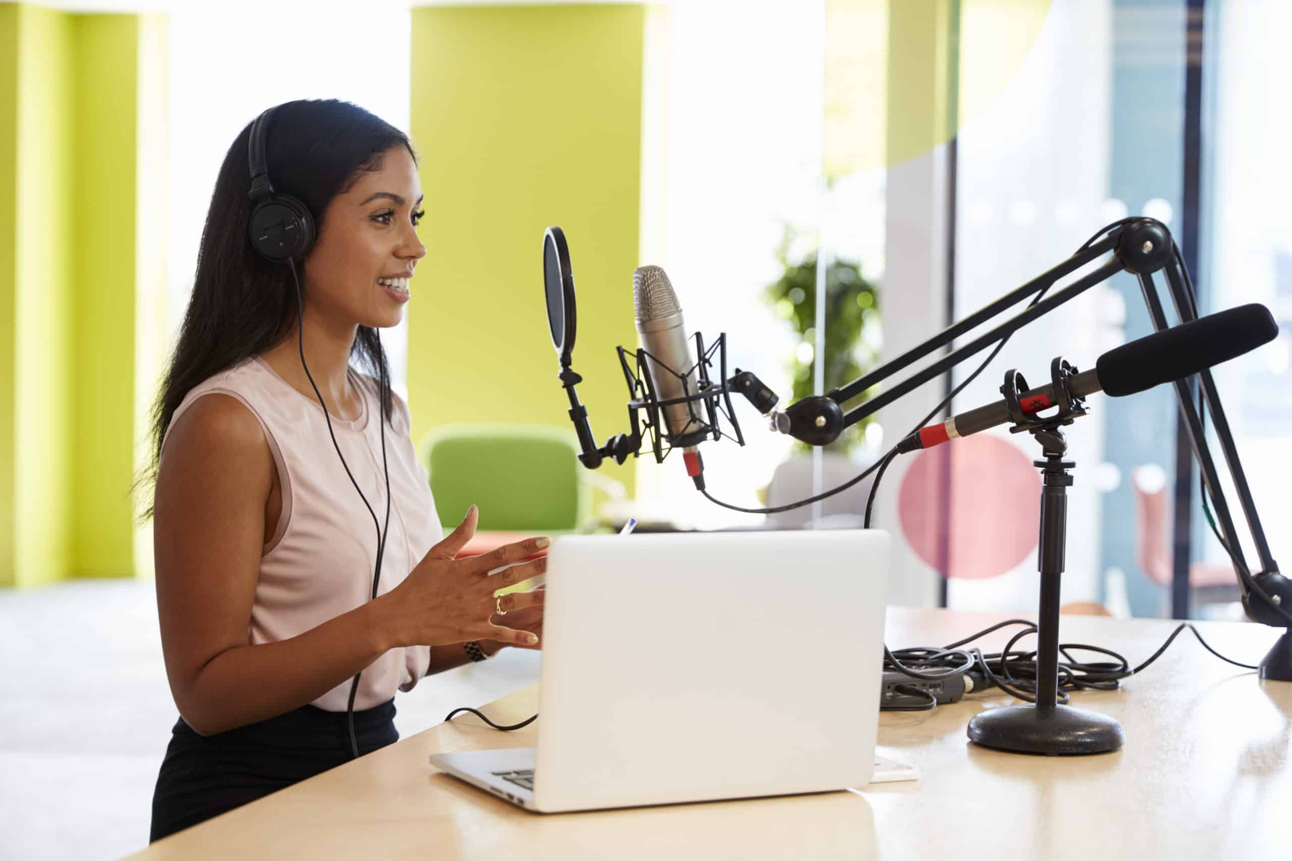 Young mixed race woman recording and transcribing a podcast in a studio