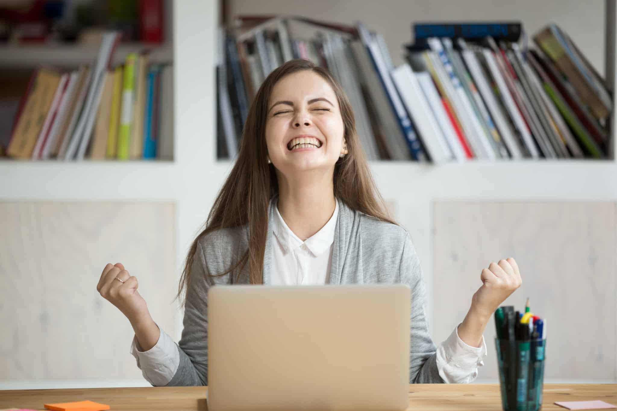 Excited female student feels euphoric celebrating online learning success thanks to video captions in education
