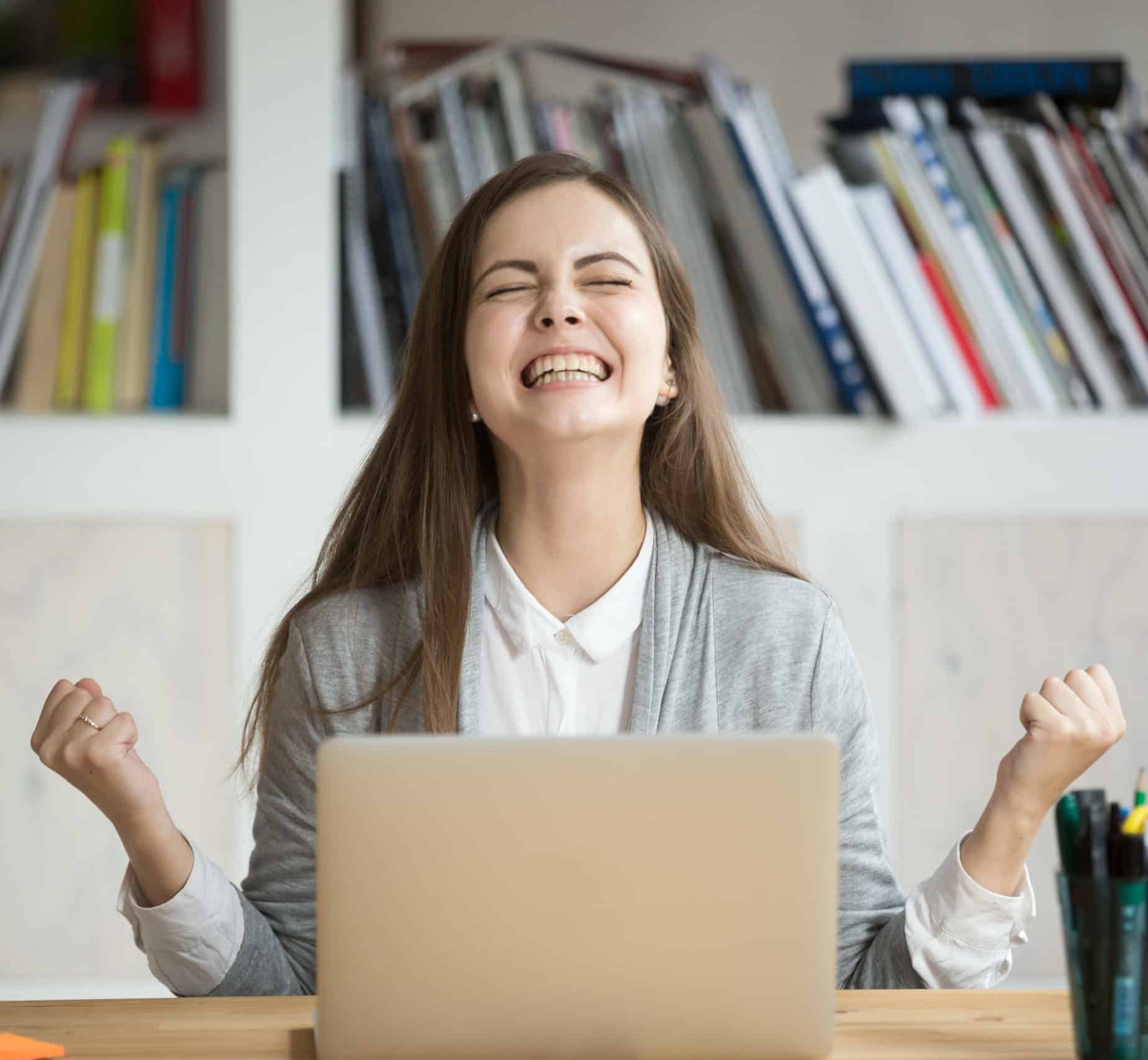 Excited female student feels euphoric celebrating online learning success thanks to video captions in education