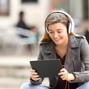 Woman sitting with headphones and looking at her tablet