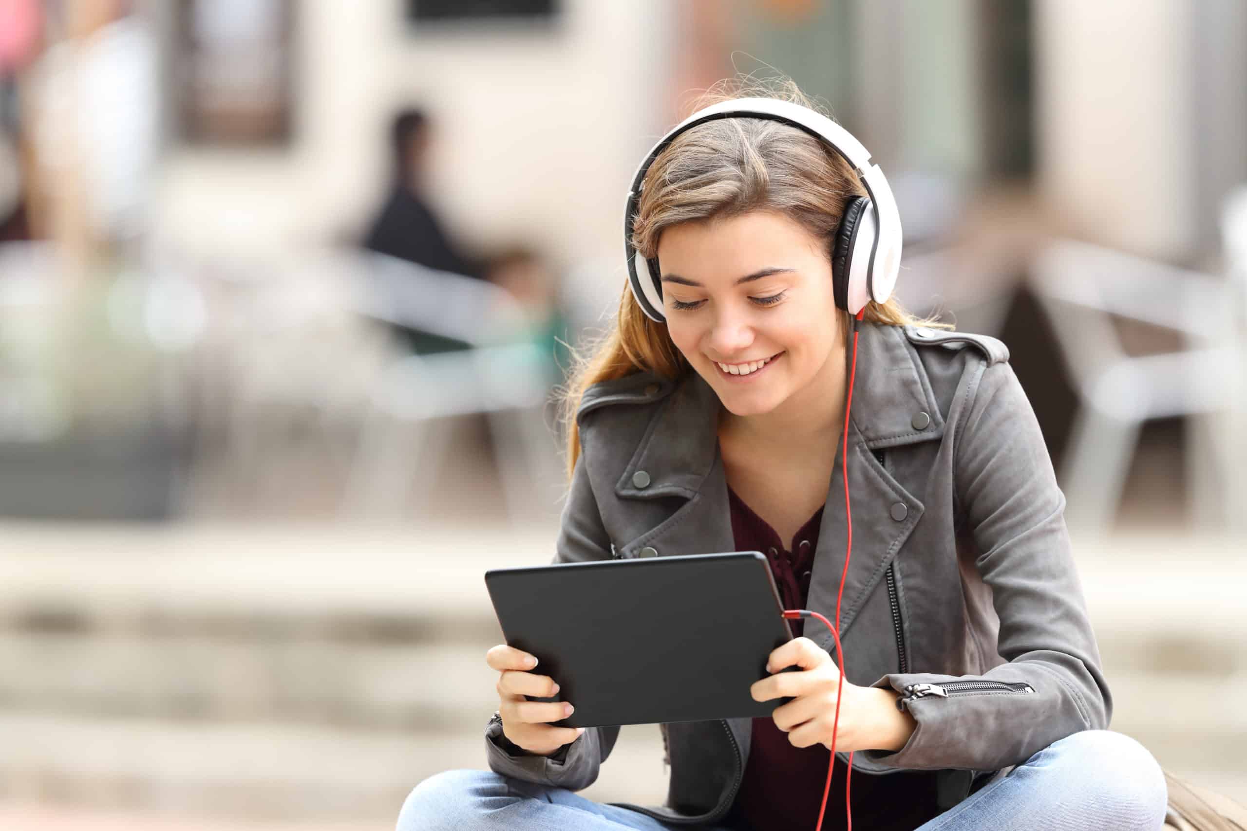 Woman sitting with headphones and looking at her tablet