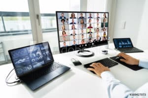 Person sitting a desk with three monitors