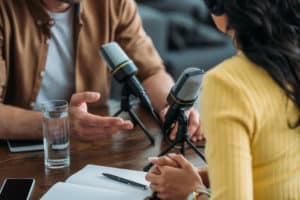 cropped view of two radio hosts recording podcast in broadcasting studio