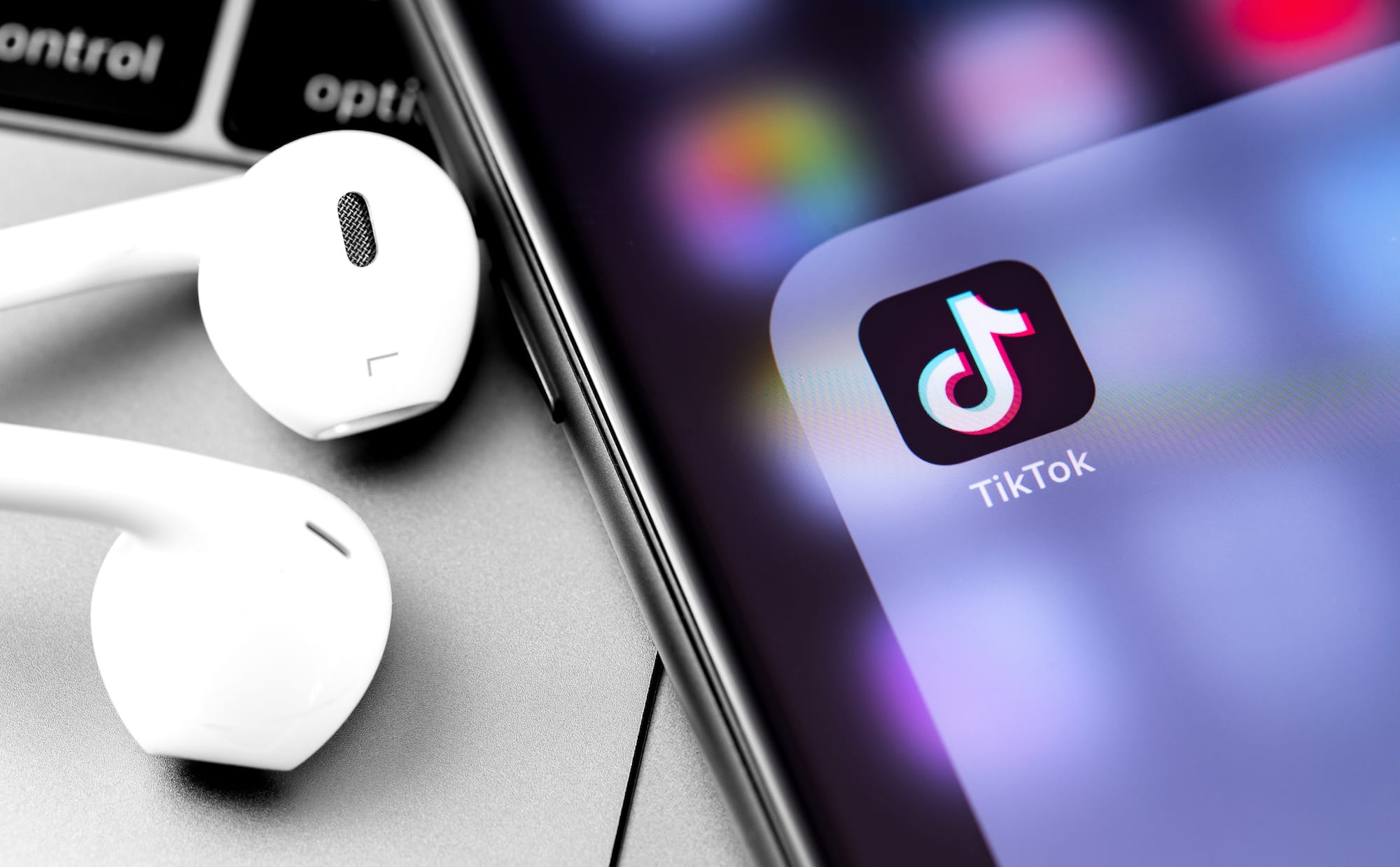 TikTok logo on the display iPhone with Earpods headphones closeup. TikTok is app to create and share videos
