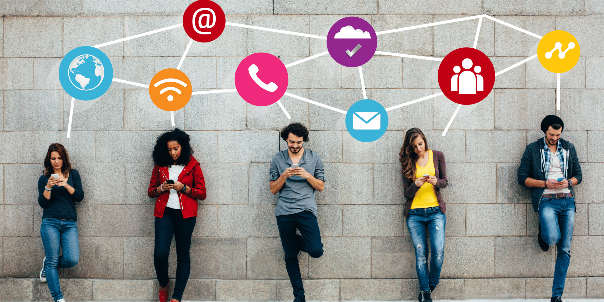 People standing along a wall together using their smartphones.